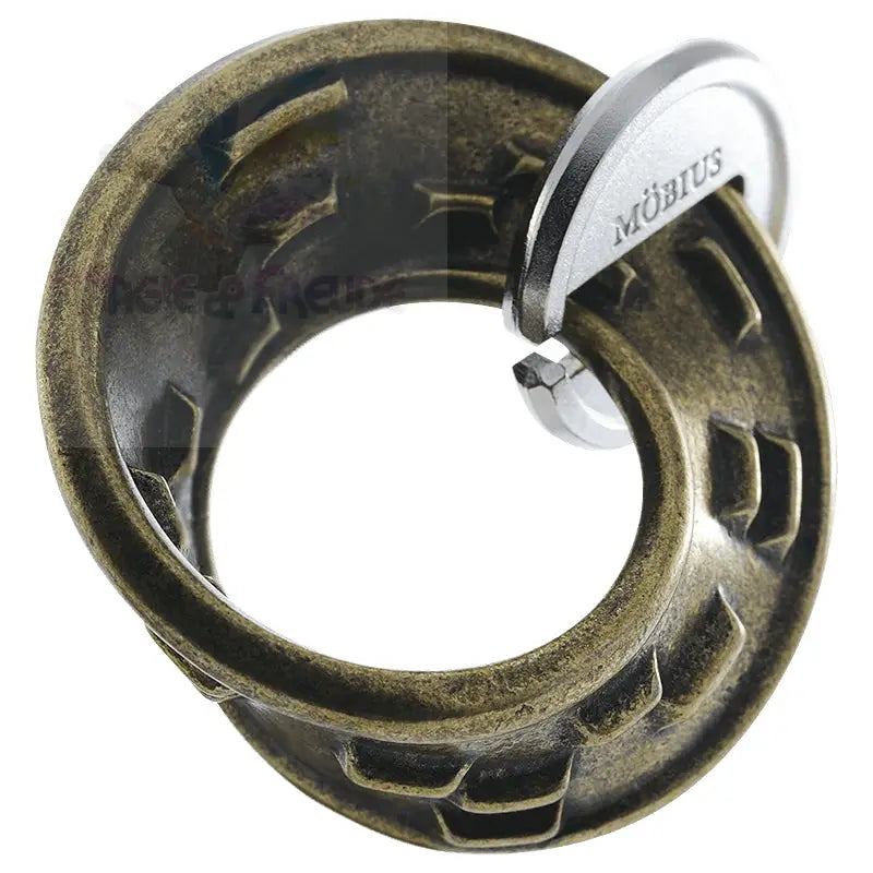 Ein antikes bronzefarbenes Metallpuzzle mit einem silberfarbenen ’Möbius’-Emblem.