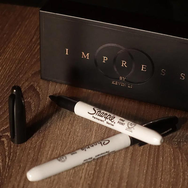 Zaubertrick-Set Impress mit zwei schwarzen Permanent-Markern auf Holztisch