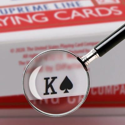 König Pik unter Lupe, Bicycle Spielkarten-Deck im Hintergrund