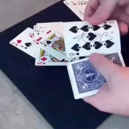 Zaubertrick mit signierten Spielkarten auf schwarzer Unterlage, Hand hält Kartendeck