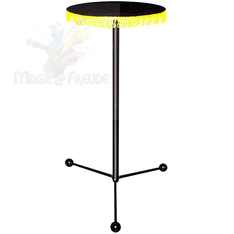Schwarzer runder Zaubertisch mit gelbem Fransenrand und dreibeinigem Fuß.