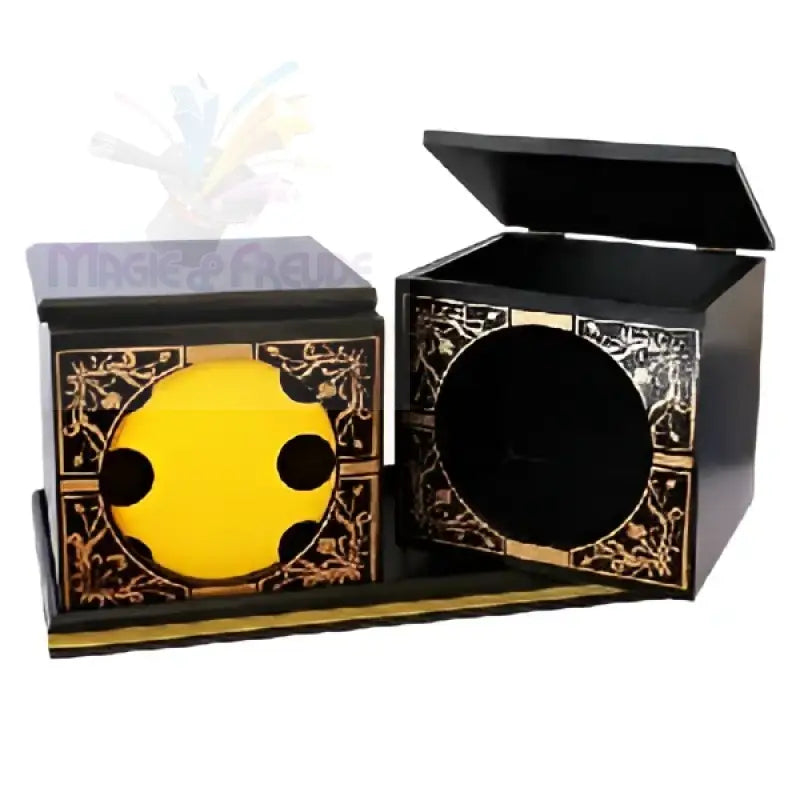 Zwei verschnörkelte schwarze Holzkisten mit goldenen Akzenten, eine davon mit einer gelben runden Öffnung mit schwarzen Tupfen, die auf einem passenden Sockel ruht.
