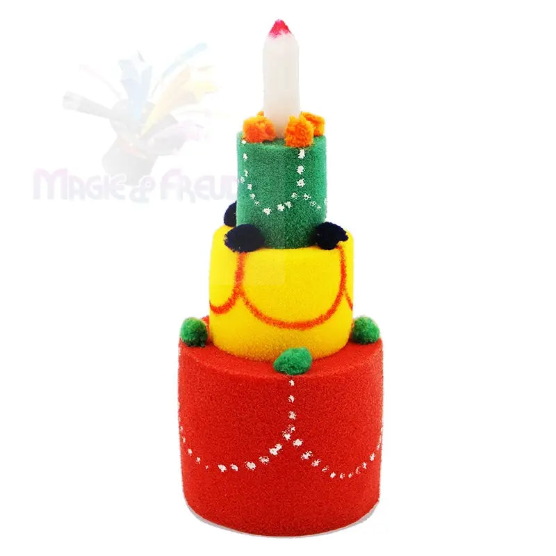 Eine dreistöckige, dekorative Torte mit einer Kerze auf der Spitze, mit roten, gelben und grünen Schichten, die mit Bommeln und weißen Perlenmustern verziert sind.