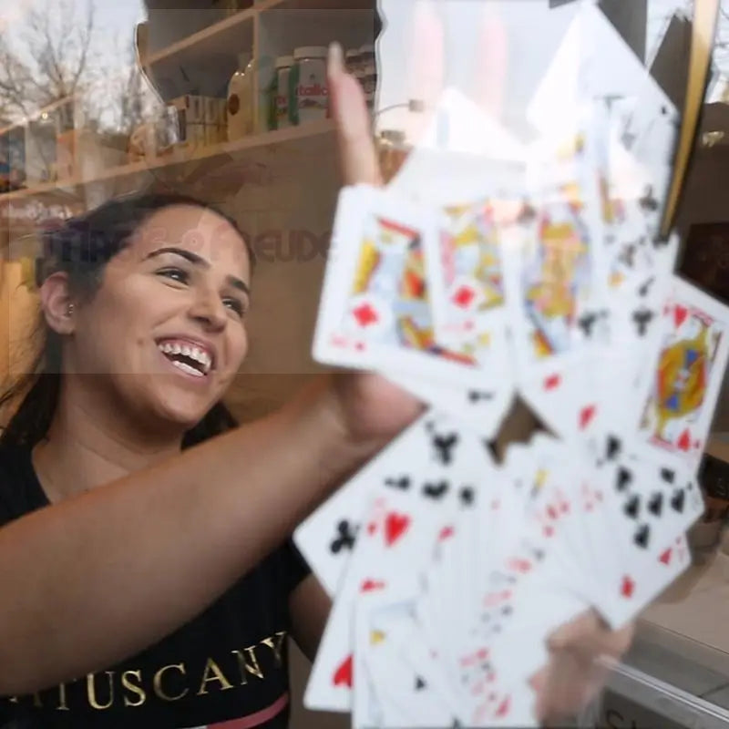 Eine Frau in einem schwarzen Hemd, die ein aufgefächertes Kartenspiel in der Hand hält.