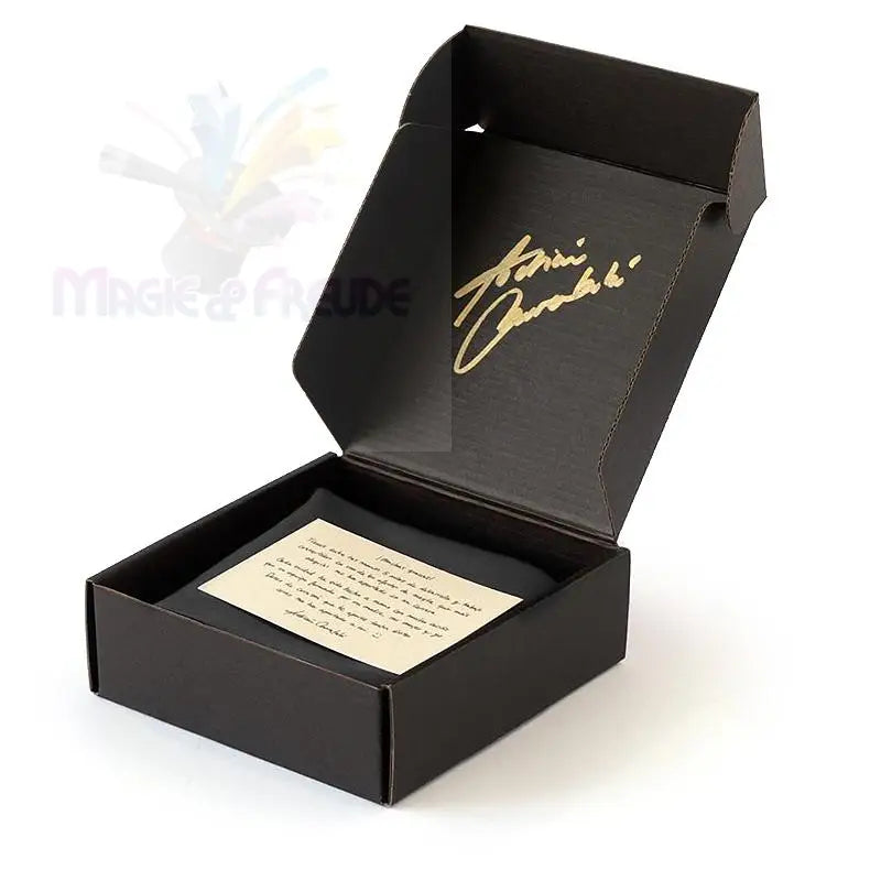 Eine offene schwarze Pappschachtel mit einer goldenen Unterschrift auf dem Deckel und einem cremefarbenen Zettel im Inneren.