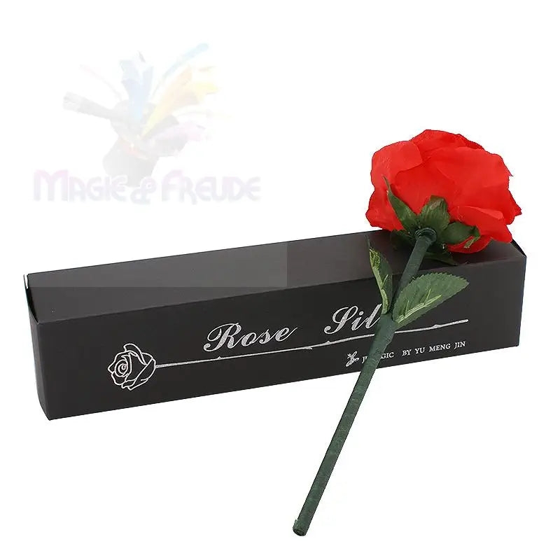 Eine einzelne künstliche rote Rose mit grünen Blättern und Stiel, die auf einer schwarzen Geschenkverpackung ruht.