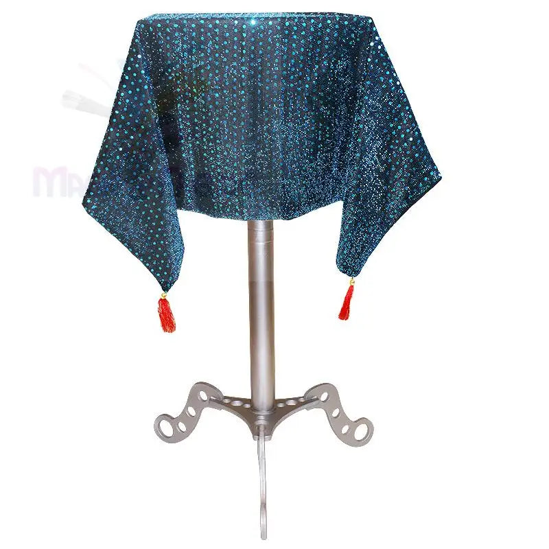 Ein tealfarbener, mit Pailletten besetzter, schwebender Zauberertisch mit roten Quasten.