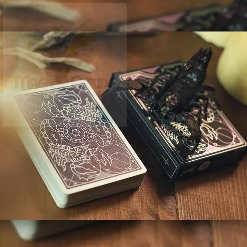 Ein Spielkartenset mit einem Skorpionmotiv auf der Rückseite und einer passenden Aufbewahrungsbox, die mit einem Skorpion verziert ist.