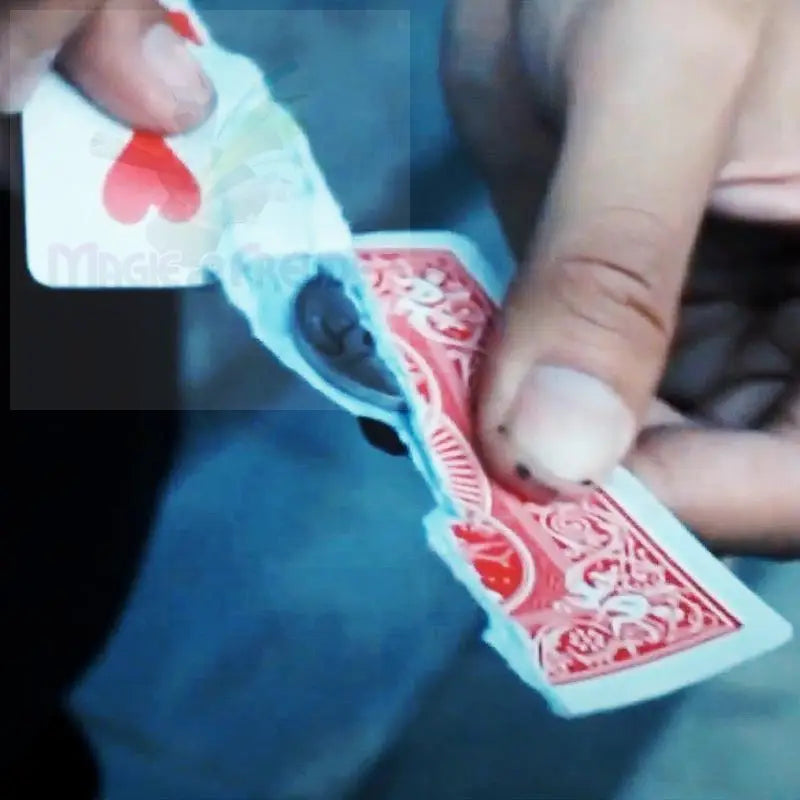 Eine zerrissene Spielkarte, die ein verstecktes Fach mit einem kleinen, dunklen Gegenstand darin offenbart.