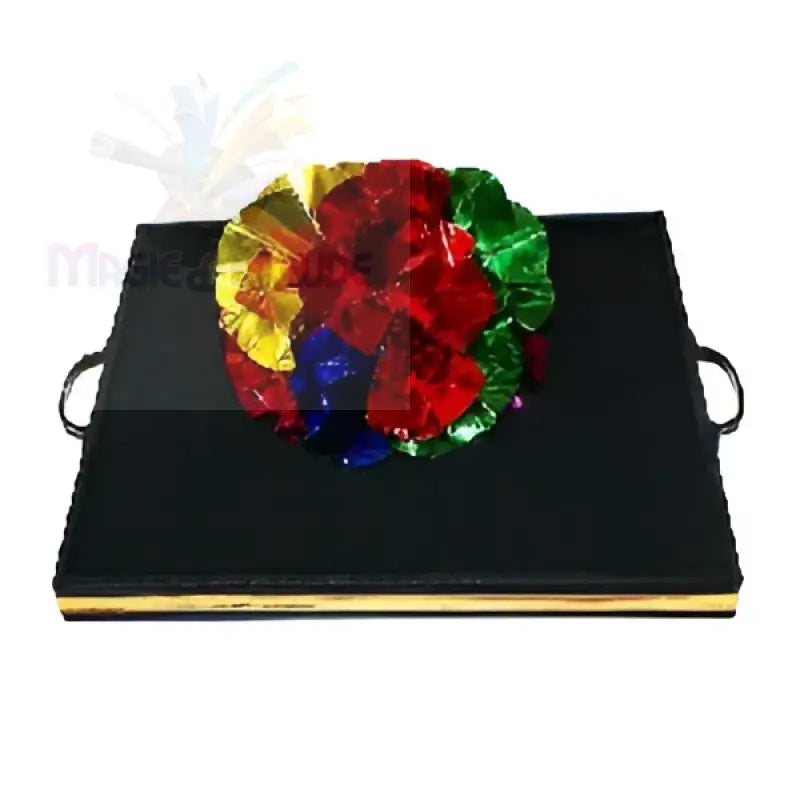Ein schwarzes, rechteckiges Tablett mit Griffen, das von einer bunten, zerknitterten Folienblume gekrönt wird.