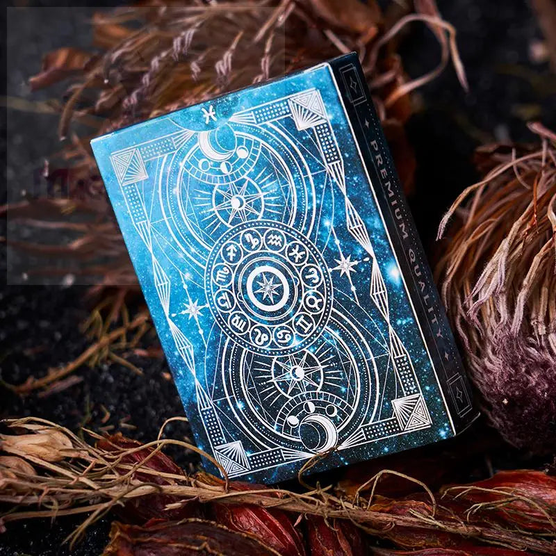 Ein Spielkartensatz mit einer blau-schwarzen kosmischen Tuck-Box mit weißen astrologischen und himmlischen Motiven.