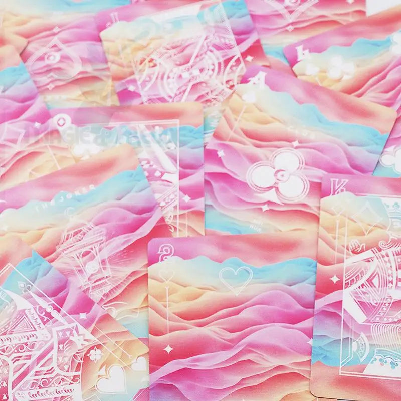 Eine verstreute Sammlung von pastellfarbenen Spielkarten mit abstrakten und fantasievollen weißen Umrissen.