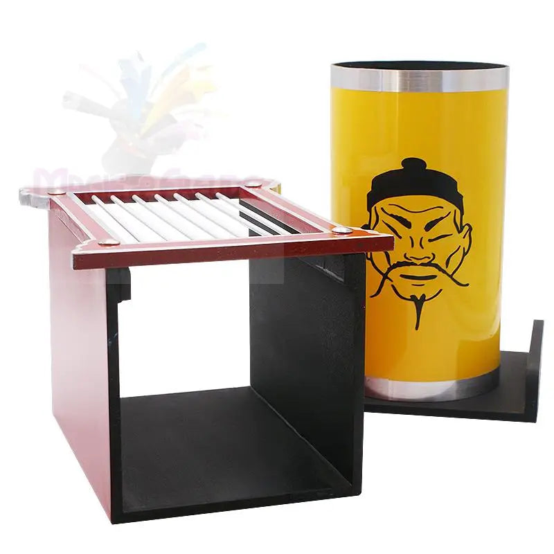 Eine rot-schwarze Holzkiste mit einem Lattenrost und einem gelben Zylinder mit einer Zeichnung eines Männergesichts.