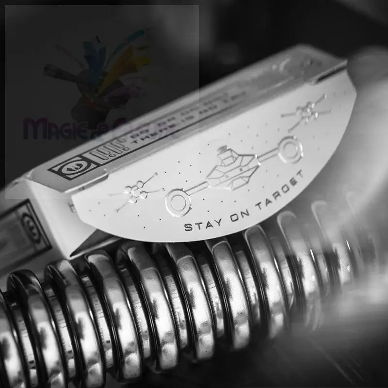 Metallische, rechteckige Spielkartenschachtel mit halbrunder, geprägter Klappe mit Raumschiffmotiv und der Aufschrift ’STAY ON TARGET’.