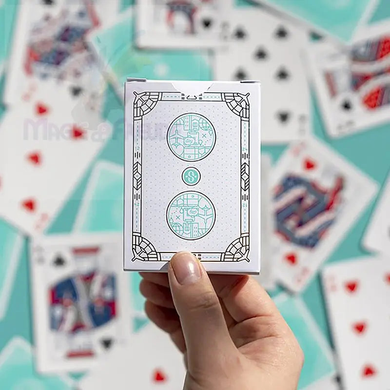 Eine weiße Spielkartenschachtel mit einem von der Art déco inspirierten Design in Schwarz und Teal.