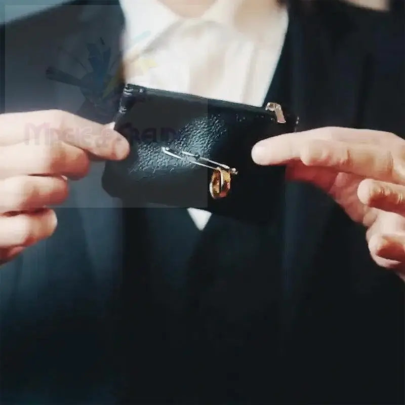 Schwarzes strukturiertes Lederportemonnaie mit einer Sicherheitsnadel und einem goldenen Ring.