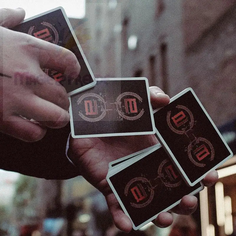 Eine Hand hält mehrere schwarze Spielkarten mit einem rot-weißen Kreismuster.