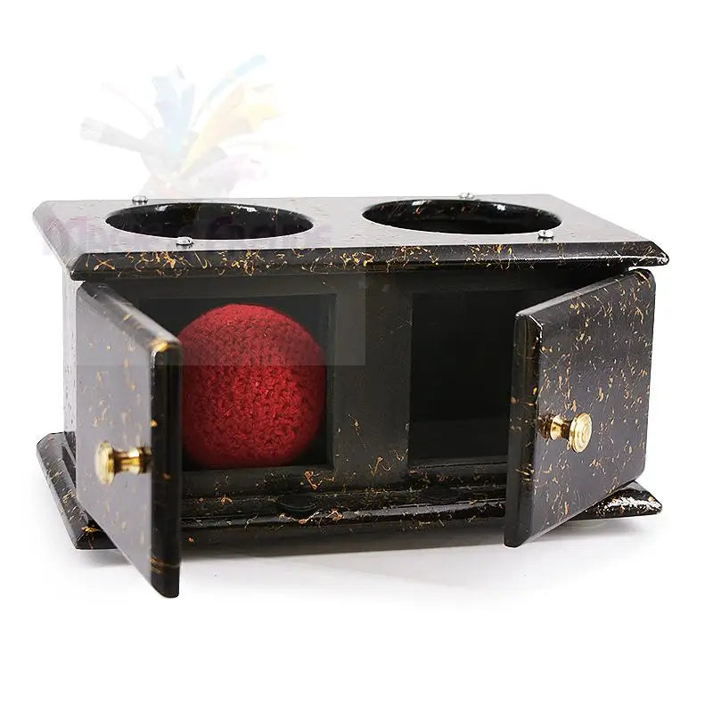 Ein schwarz-gold marmorierter Zauberkasten mit zwei offenen Fächern, von denen eines eine rote Schwammkugel enthält.