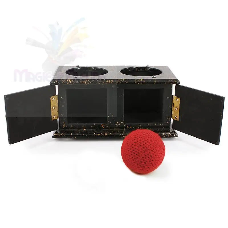 Ein schwarzes Holzkästchen mit zwei Fächern und zwei offenen Türen, begleitet von einem roten, gestrickten Ball.