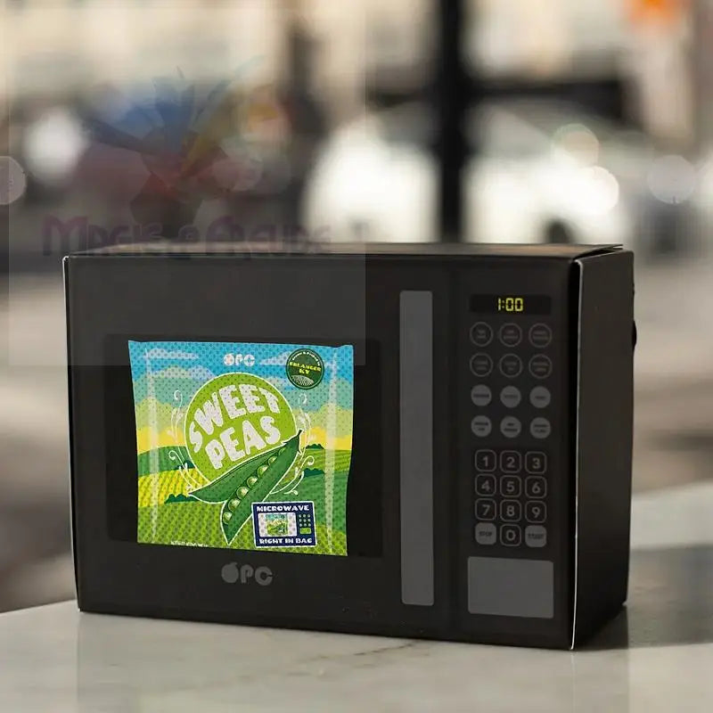 Eine schwarze Spielzeugmikrowelle mit einem Bildschirm, auf dem eine Tüte mit Zuckererbsen zu sehen ist.