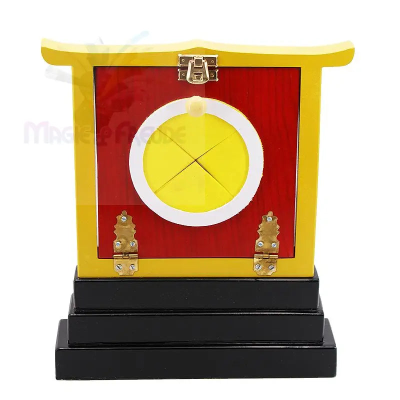 Ein rot-gelber Zauberkasten aus Holz mit einer runden Öffnung und einem Verschluss oben.