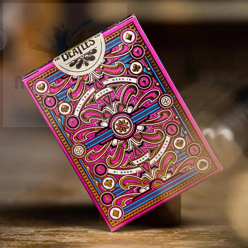 Ein magentafarbenes und goldenes Spielkartenset mit verschlungenen, psychedelischen Motiven.