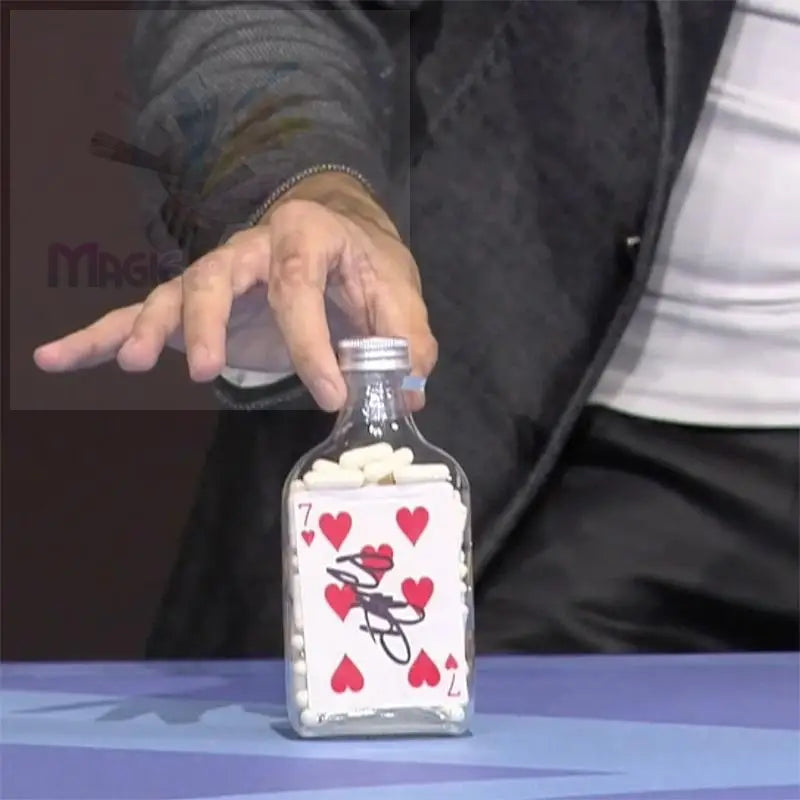 Glasflasche gefüllt mit weißen Pillen und einer Spielkarte.