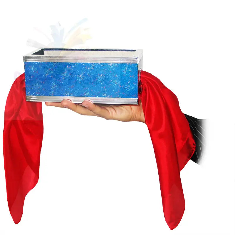 Eine Zauberkiste mit blau gemusterten Seiten, die in einer Hand gehalten wird und an deren beiden Enden roter Stoff herunterhängt.