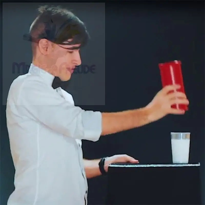 Eine Person hält einen roten Shaker über ein Glas mit Milch.