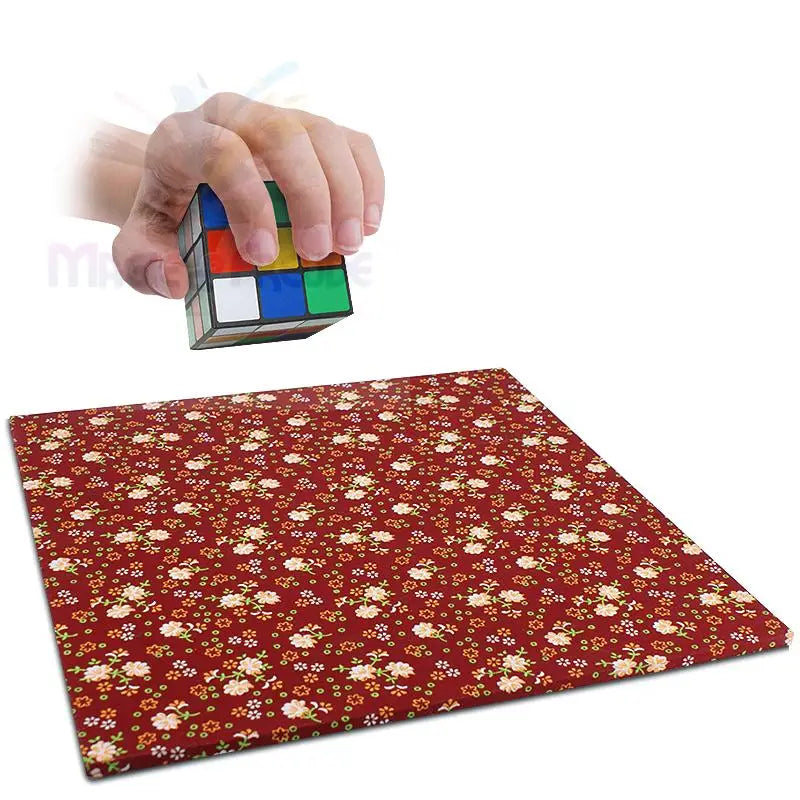 Eine Hand hält einen Zauberwürfel über einer blumengemusterten Fläche.